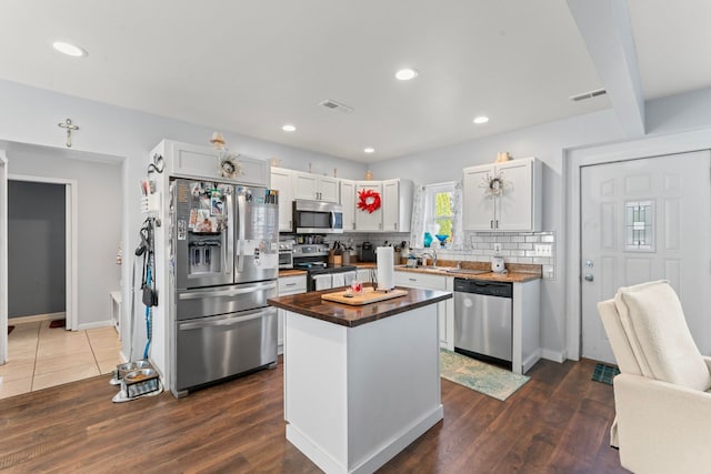 kitchen featuring visible vents, dark wood finished floors, stainless steel appliances, decorative backsplash, and butcher block counters