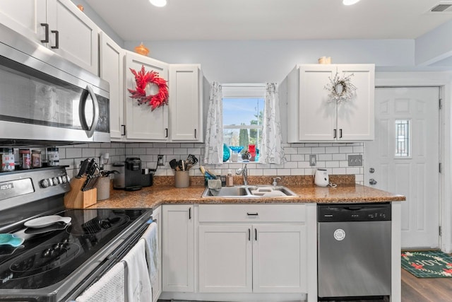 kitchen featuring tasteful backsplash, visible vents, appliances with stainless steel finishes, white cabinetry, and a sink