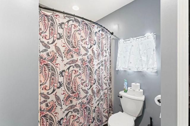 bathroom with a shower with shower curtain and toilet