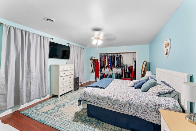 bedroom featuring ceiling fan, visible vents, a closet, and wood finished floors