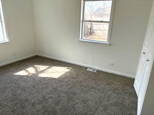 unfurnished room with visible vents, baseboards, and carpet flooring