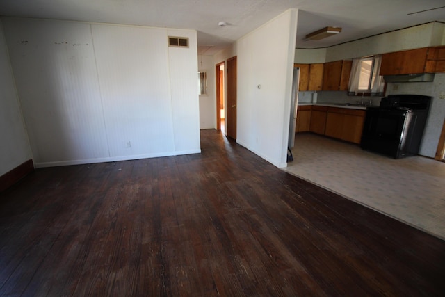 unfurnished living room featuring baseboards, visible vents, dark wood-style flooring, and a sink