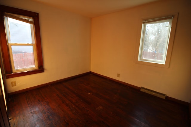 unfurnished room with dark wood-style floors, visible vents, a healthy amount of sunlight, and baseboards