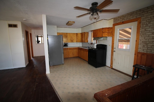 kitchen featuring visible vents, ceiling fan, freestanding refrigerator, black electric range oven, and a sink