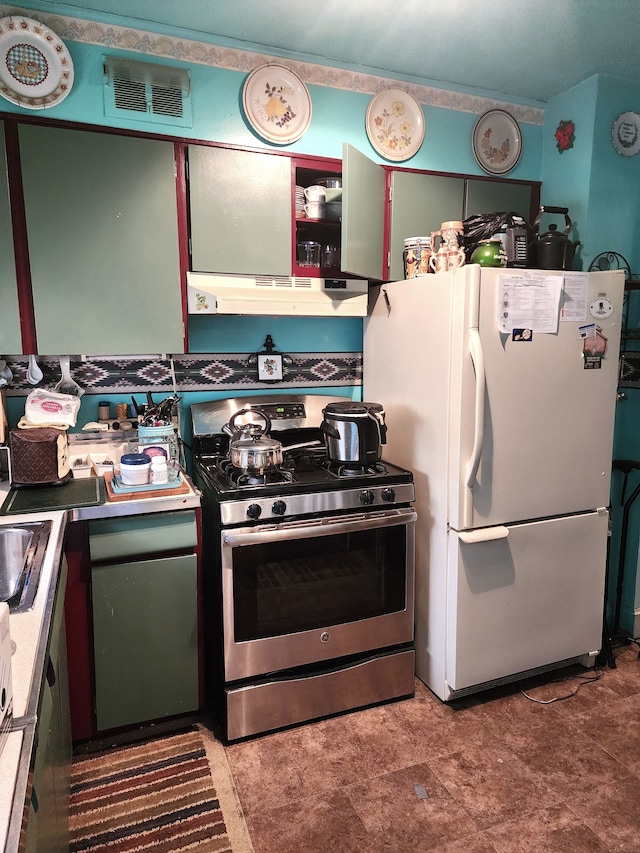 kitchen with under cabinet range hood, visible vents, stainless steel gas range, and freestanding refrigerator