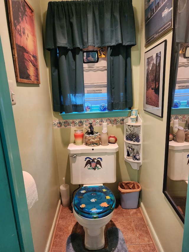 half bathroom with tile patterned flooring, toilet, and baseboards