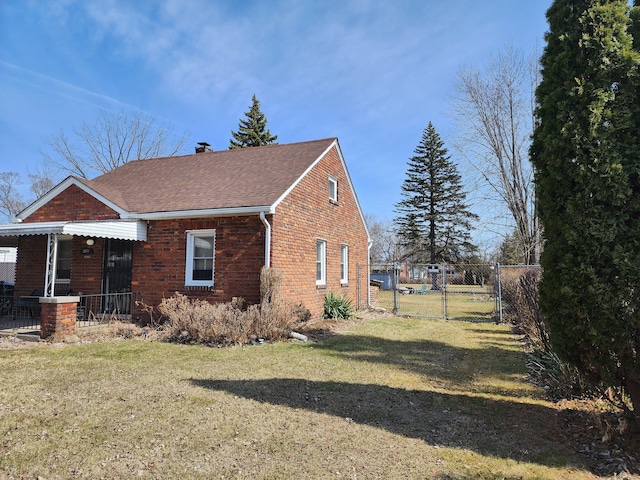 view of side of property with brick siding, fence, a chimney, a yard, and a gate