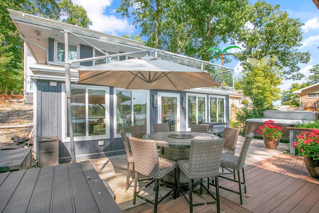 wooden terrace featuring outdoor dining space and a hot tub