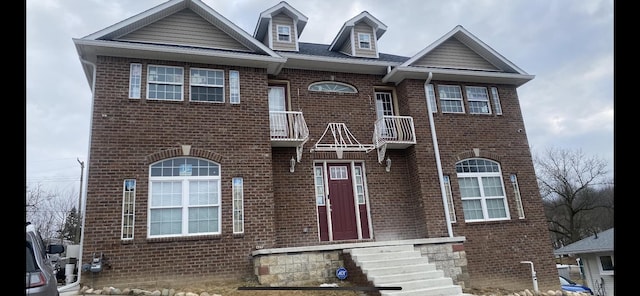 view of front of property with brick siding and a balcony