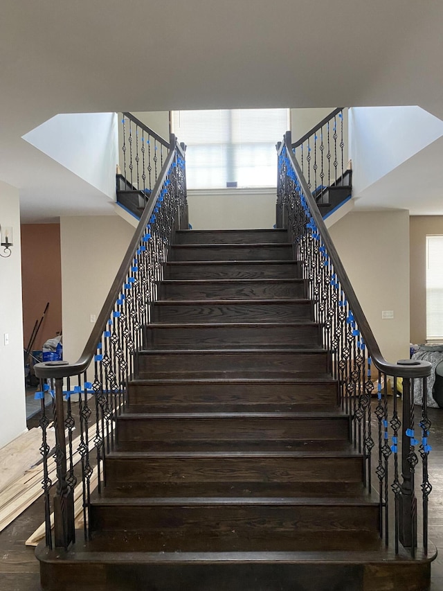 stairway featuring a high ceiling and wood finished floors