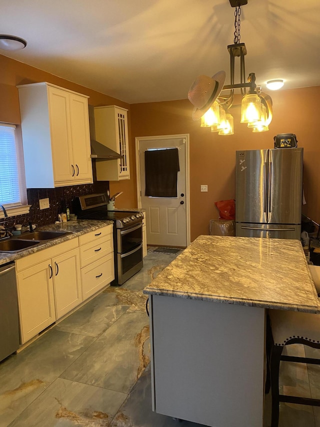 kitchen with a sink, tasteful backsplash, a kitchen island, white cabinetry, and appliances with stainless steel finishes