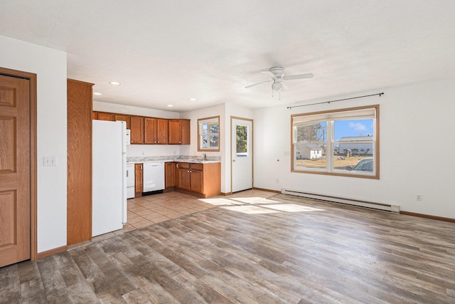 kitchen featuring white appliances, wood finished floors, light countertops, brown cabinets, and baseboard heating