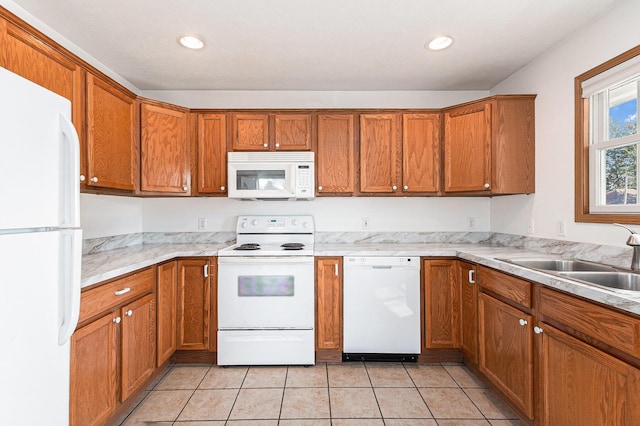 kitchen featuring light tile patterned floors, recessed lighting, brown cabinets, white appliances, and a sink