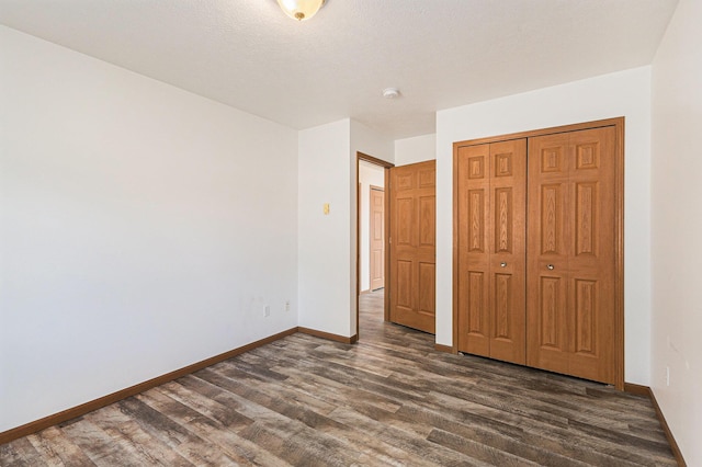 unfurnished bedroom with dark wood-type flooring, baseboards, and a closet