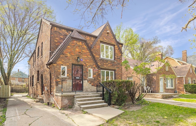 english style home featuring fence and brick siding