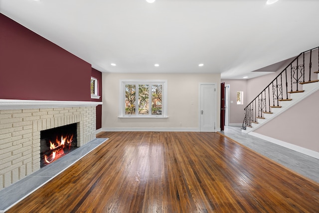 unfurnished living room featuring a fireplace, baseboards, stairway, recessed lighting, and hardwood / wood-style flooring