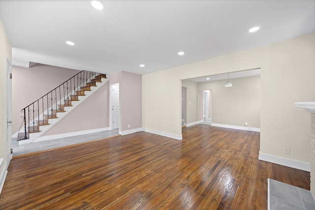 unfurnished living room featuring a fireplace, stairs, recessed lighting, baseboards, and hardwood / wood-style flooring