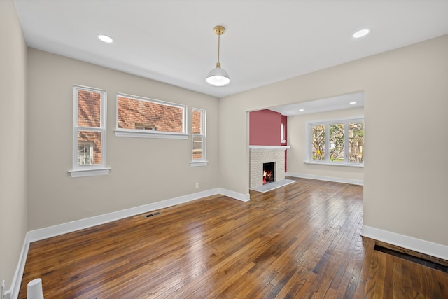 unfurnished living room featuring baseboards, dark wood finished floors, visible vents, and a fireplace