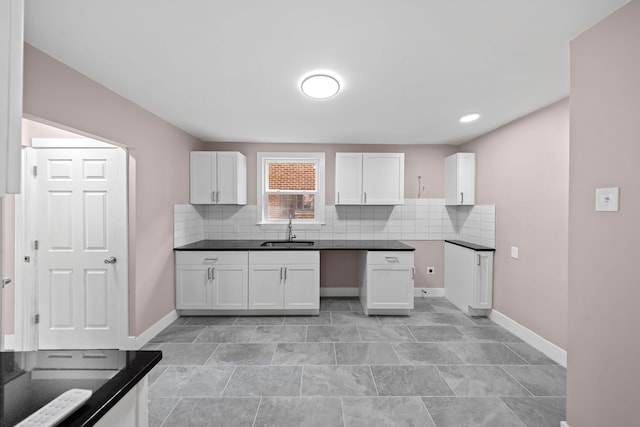 kitchen featuring a sink, baseboards, tasteful backsplash, and white cabinets