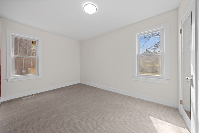 carpeted empty room featuring plenty of natural light, baseboards, and visible vents