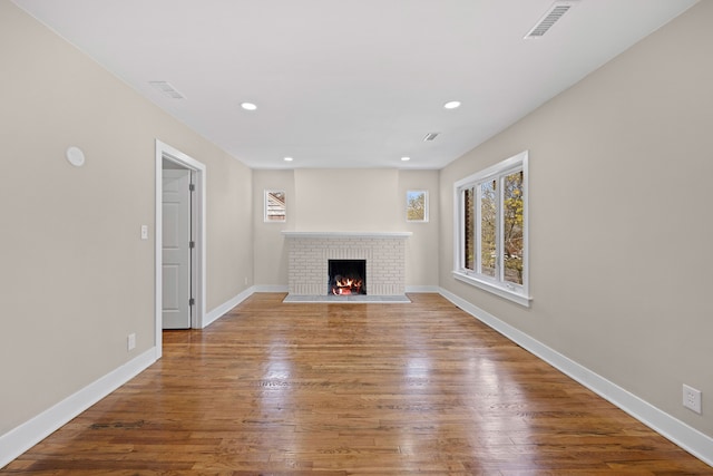 unfurnished living room featuring recessed lighting, a brick fireplace, and wood finished floors