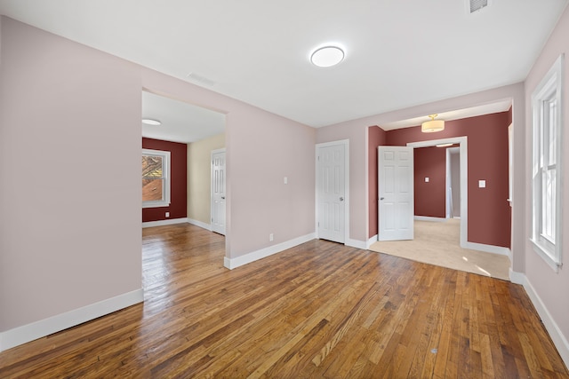 spare room with baseboards, light wood-style flooring, and visible vents