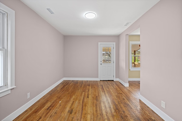 unfurnished room with baseboards, hardwood / wood-style floors, and visible vents