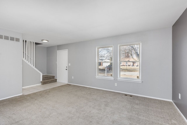 interior space with light carpet, visible vents, stairway, and baseboards