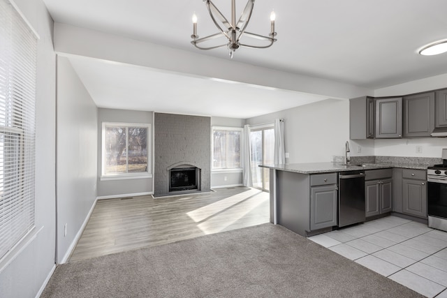 kitchen featuring gray cabinetry, light carpet, appliances with stainless steel finishes, a peninsula, and an inviting chandelier