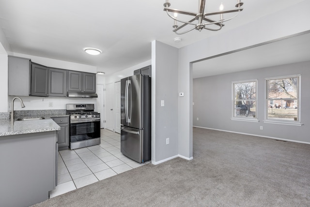 kitchen featuring a sink, under cabinet range hood, appliances with stainless steel finishes, light colored carpet, and a chandelier