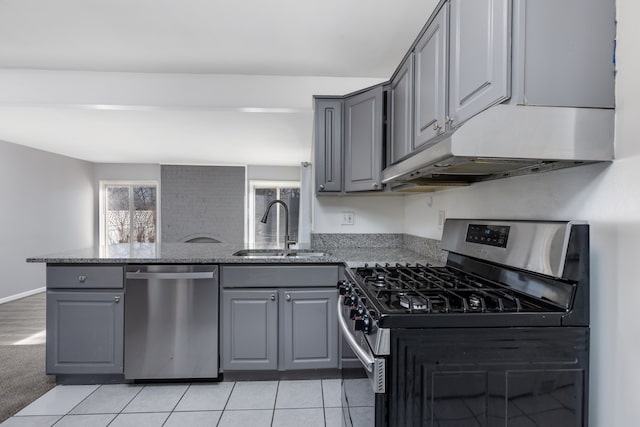 kitchen with a peninsula, gray cabinets, a sink, stainless steel appliances, and under cabinet range hood