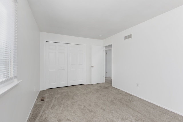 unfurnished bedroom with carpet, visible vents, a closet, and baseboards