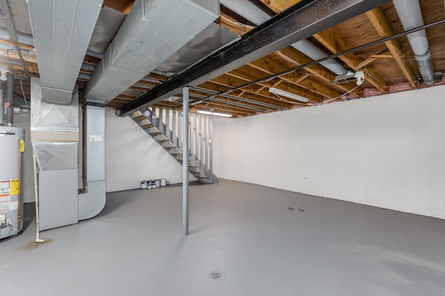 unfinished basement featuring stairway, heating unit, and water heater