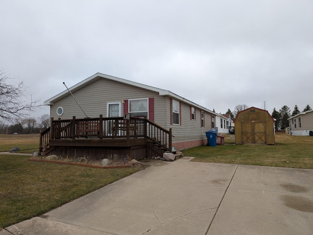 manufactured / mobile home featuring a storage unit, a deck, an outdoor structure, and a front yard