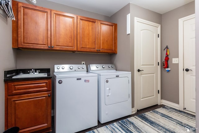 clothes washing area with a sink, baseboards, cabinet space, and washer and dryer