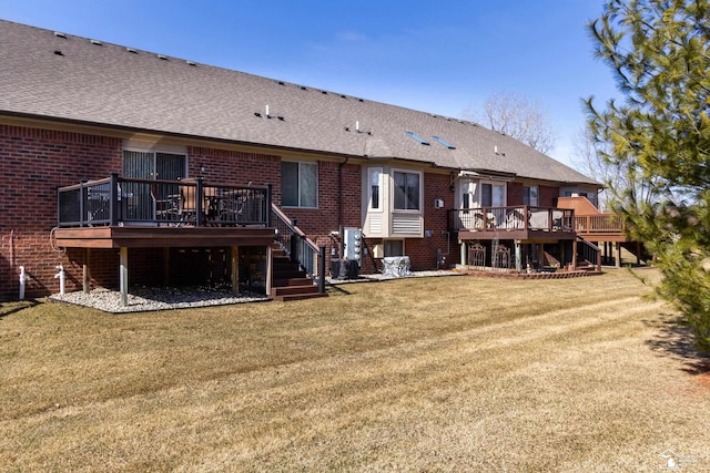 rear view of house featuring stairway, a yard, brick siding, and a wooden deck