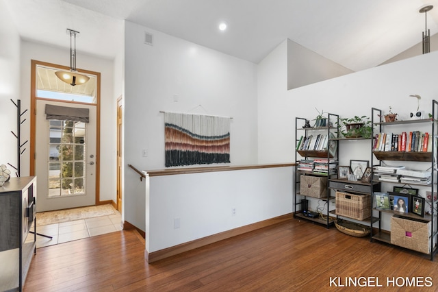 misc room with vaulted ceiling, wood finished floors, baseboards, and visible vents