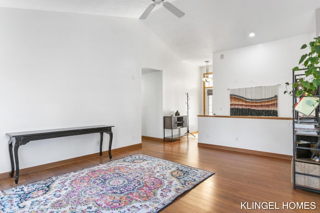 interior space with vaulted ceiling, a ceiling fan, baseboards, and wood-type flooring