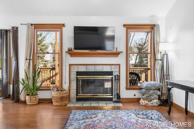 living room featuring wood finished floors, baseboards, and a tile fireplace