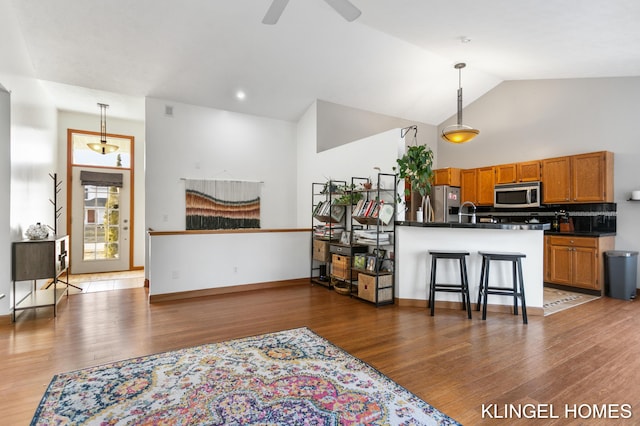 kitchen with dark countertops, brown cabinets, appliances with stainless steel finishes, and pendant lighting