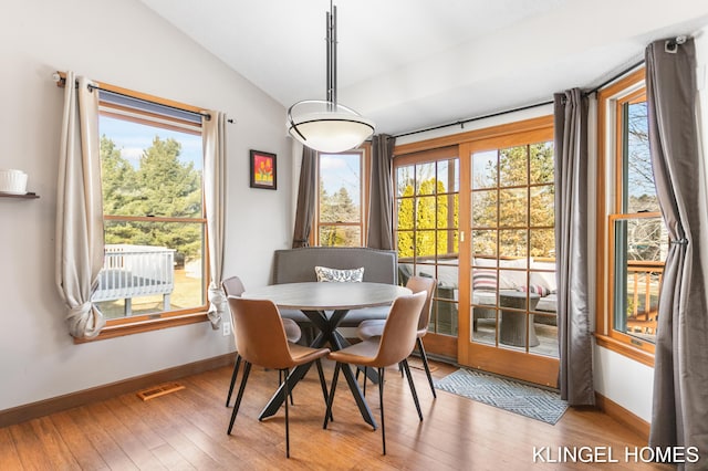 dining space featuring lofted ceiling, hardwood / wood-style flooring, baseboards, and visible vents