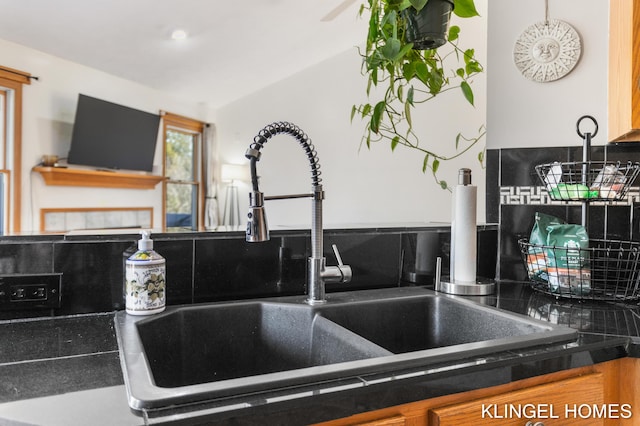 details featuring a sink, decorative backsplash, and dark countertops