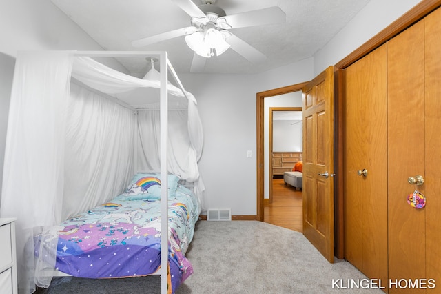 carpeted bedroom with a closet, visible vents, baseboards, and ceiling fan