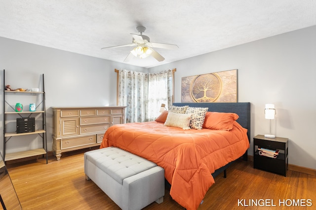 bedroom featuring baseboards, a textured ceiling, wood finished floors, and a ceiling fan