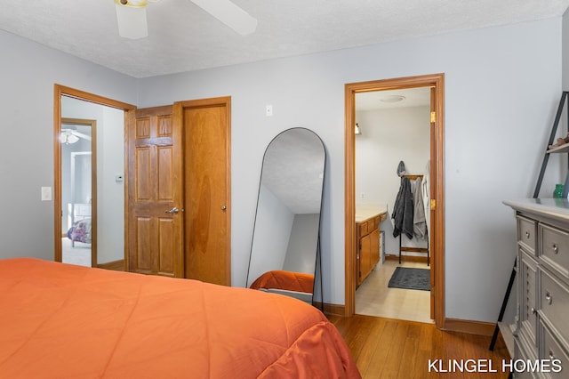 bedroom featuring a textured ceiling, ensuite bathroom, baseboards, and wood finished floors