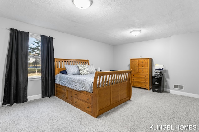 bedroom featuring a textured ceiling, baseboards, visible vents, and light carpet