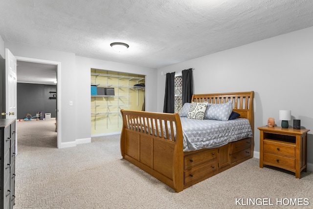 bedroom featuring light carpet, a textured ceiling, and baseboards