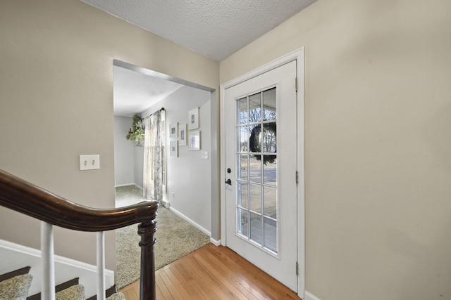 foyer entrance featuring stairway, baseboards, a textured ceiling, and hardwood / wood-style flooring