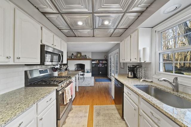 kitchen with a sink, an ornate ceiling, backsplash, white cabinetry, and stainless steel appliances