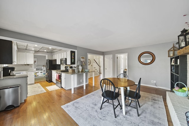 dining room featuring stairway, baseboards, and light wood finished floors